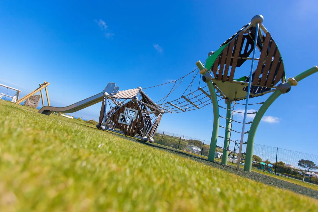 Climbing frame and slide with green grass and bright blue sky